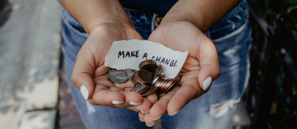 'Make a change' piece of paper with coins in a persons hands