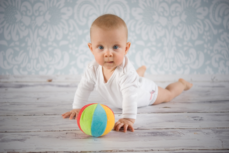 Ball games 1 baby on it's tummy with a soft toy ball