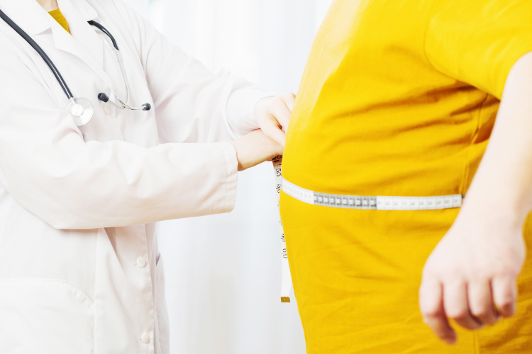 Waistline 2 man in yellow t-shirt getting his waist measured by a doctor