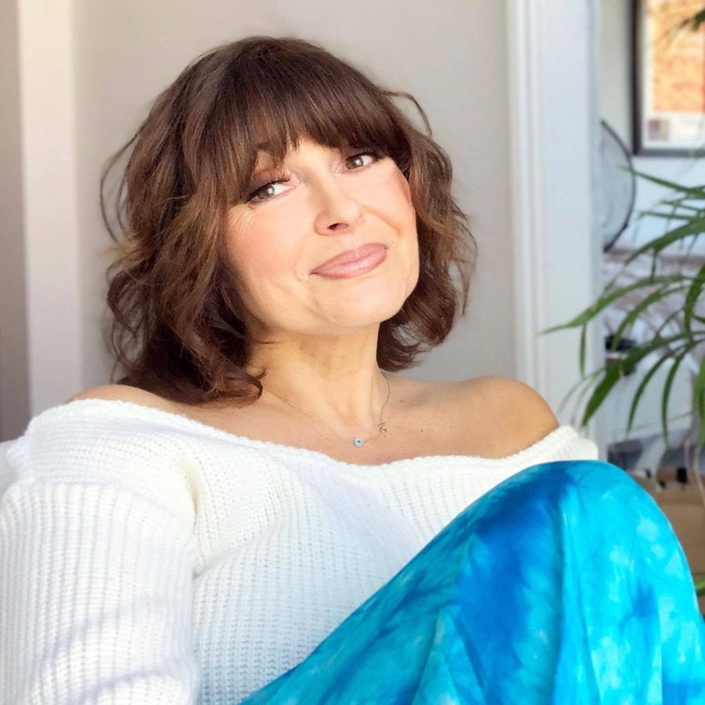 Sally bee dressed in a white wool jumper smiling