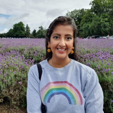 Kreena 2 A woman wearing a rainbow jumper smiling in front of a lavender field