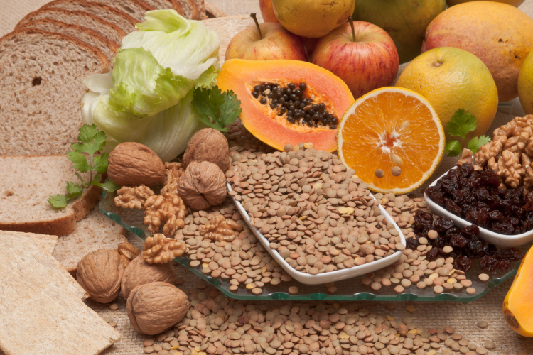 table with brown bread, fruit, lettuce, nuts and lentils