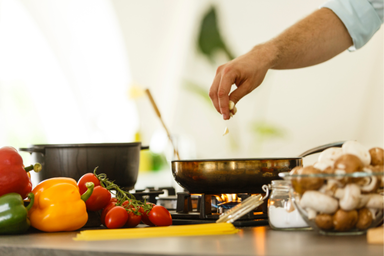 hidden sugars 3 kitchen counter with vegetables and hand dropping garlic into frying pan