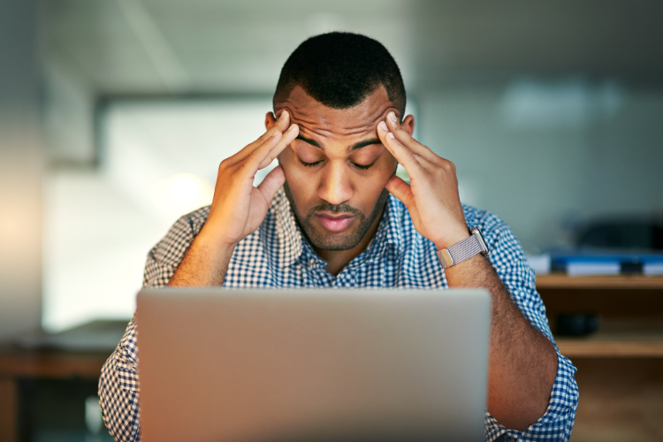 man sat by laptop looking stressed