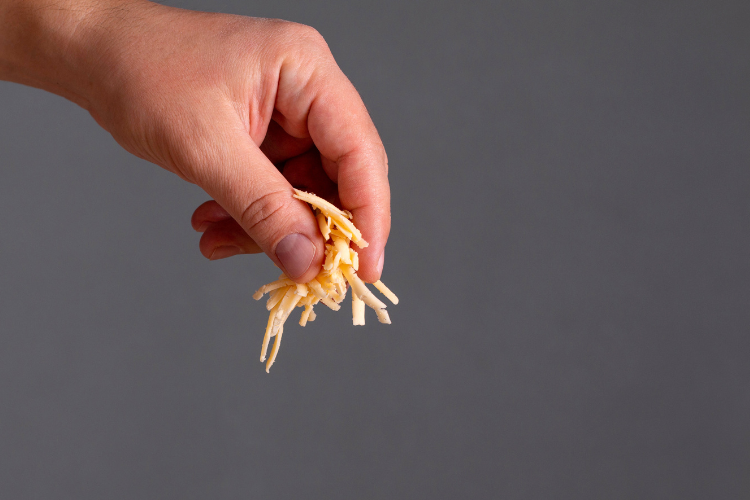 01 a hand sprinkling grated cheese