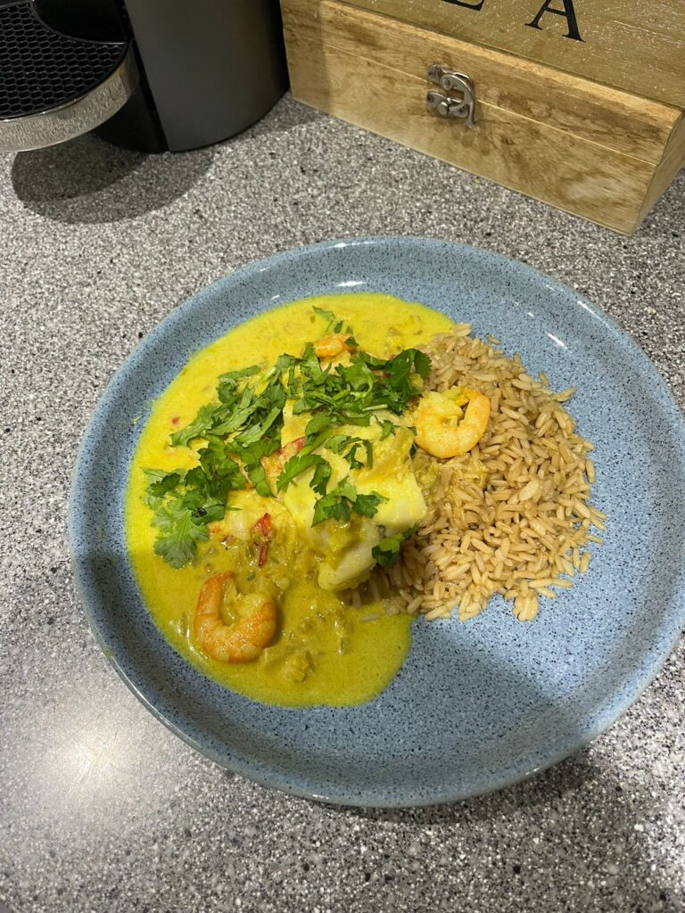 a blue plate with a coconut prawn and hake curry served on it