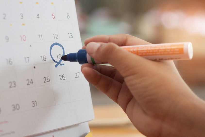 Holidays 3 Calendar with a hand and a blue marker circling a date