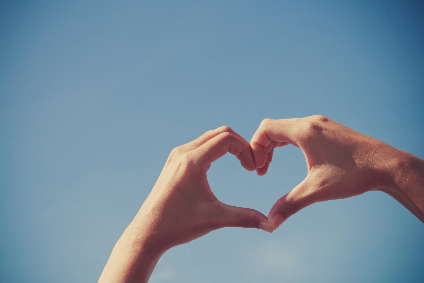 Hands in a heart shape, with sky background