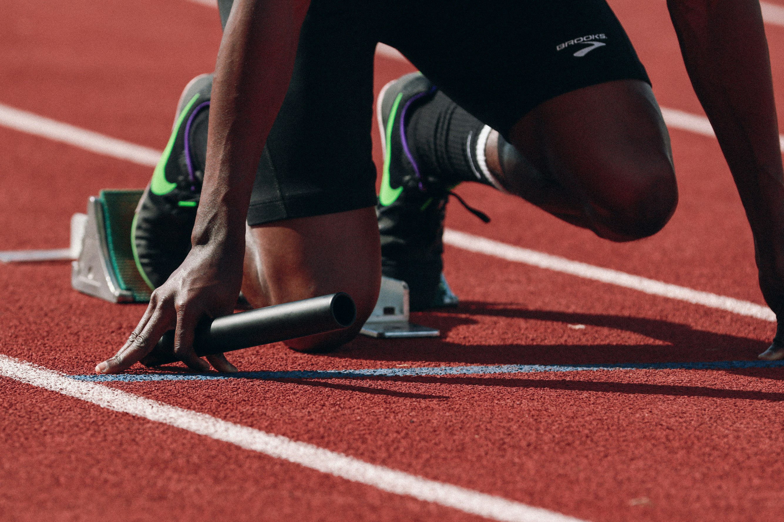 pic 3 A runner in position to start a race, holding a baton.