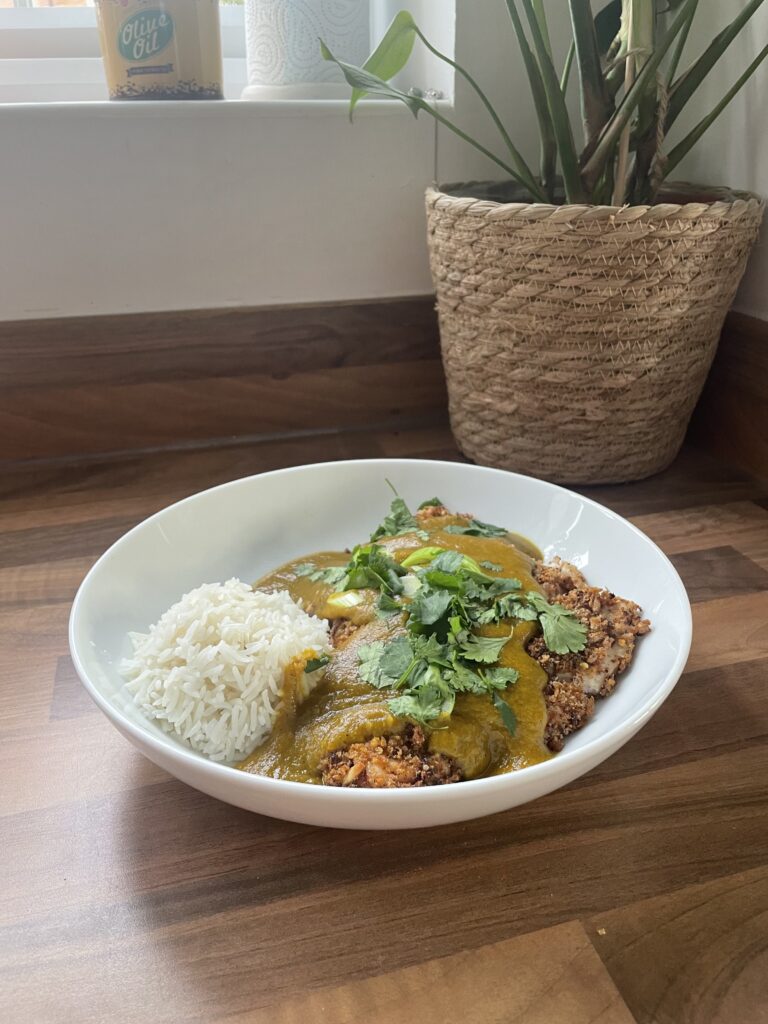 White bowl on a wooden table with Katsu chicken curry and rice in
