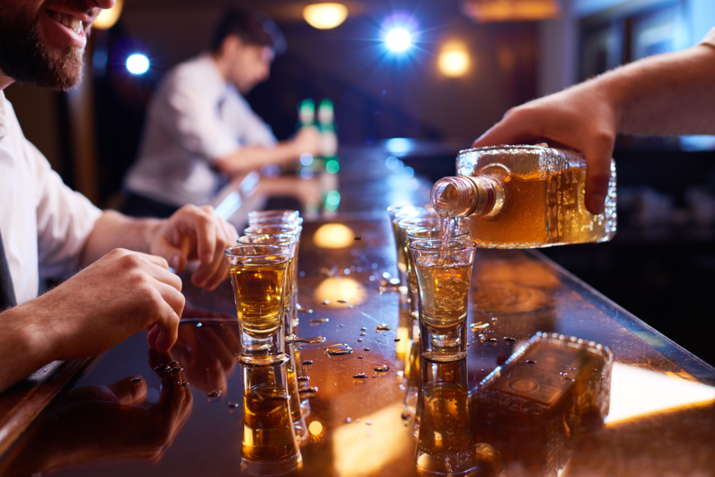 people drinking and.pouring whiskey at a bar