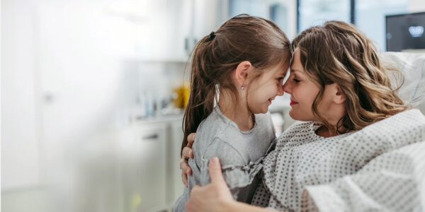 Women in a hospital gown pressing her head against her daughters